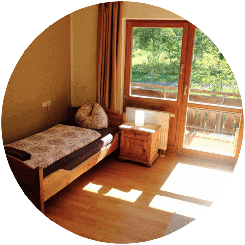 Einzelbett in Fensternähe, Holzboden, Nachttisch, Grünblick-Frauenbegleitung in der Nähe vorhanden.