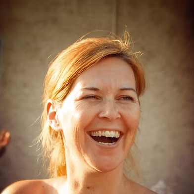 Eine Frau mit hellbraunem Haar lächelt und lacht im Freien im hellen Sonnenlicht. Eine Frau mit hellbraunem Haar lächelt und lacht im Freien im hellen Sonnenlicht.