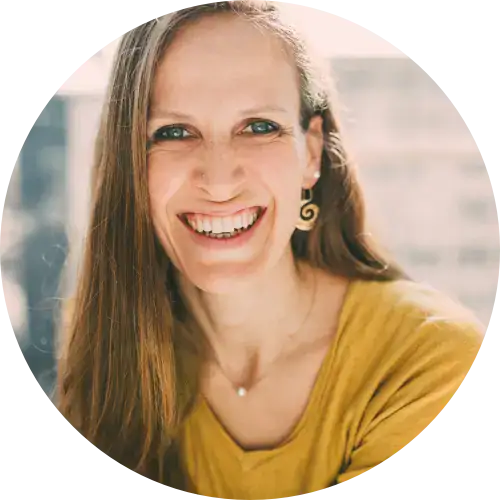 Frau mit langen braunen Haaren, lächelnd, trägt ein gelbes Oberteil und Spiralohrringe; frauenbegleitung.