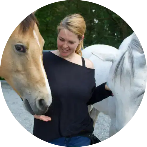 Frau füttert zwei Pferde im Freien und genießt die Frauenbegleitung entlang eines Kiesweges.