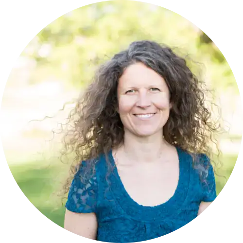 Frau mit lockigem Haar in einem blauen Top, lächelnd im Freien - perfekt für Frauenbegleitung.