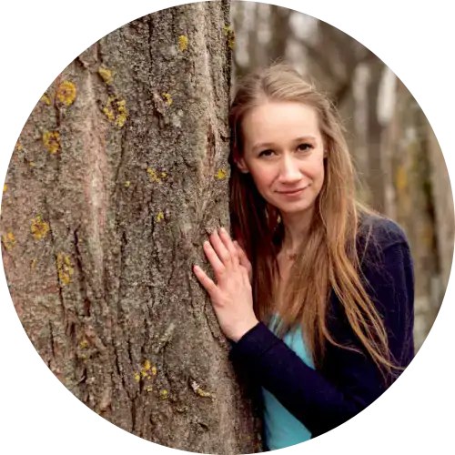 Frau mit langen Haaren, frauenbegleitung, steht an einem Baum und lächelt in die Kamera im Freien.