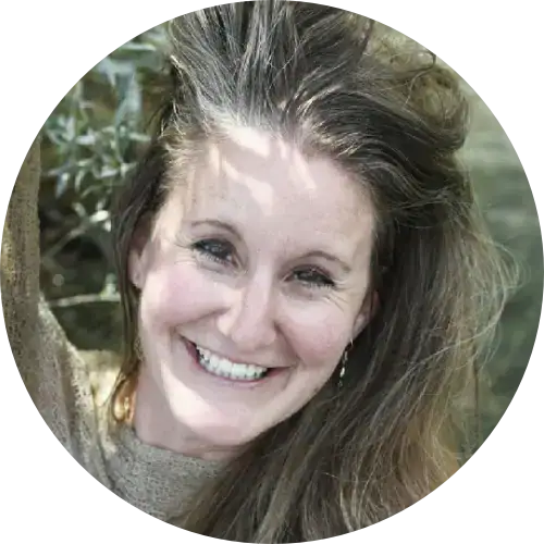 Lächelnde Frau mit langen Haaren in einem beigen Pullover, im Freien - perfekt für Frauenbegleitungsdienste.