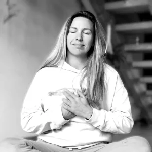 Eine Frau, die Atemarbeit praktiziert, sitzt im Schneidersitz bei einem friedlichen Breathwork Retreat 2026.